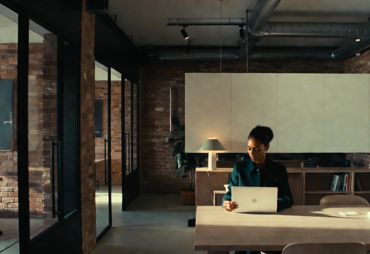 Shoreditch-style regtech office with exposed brick, glass meeting rooms, and a deep corridor