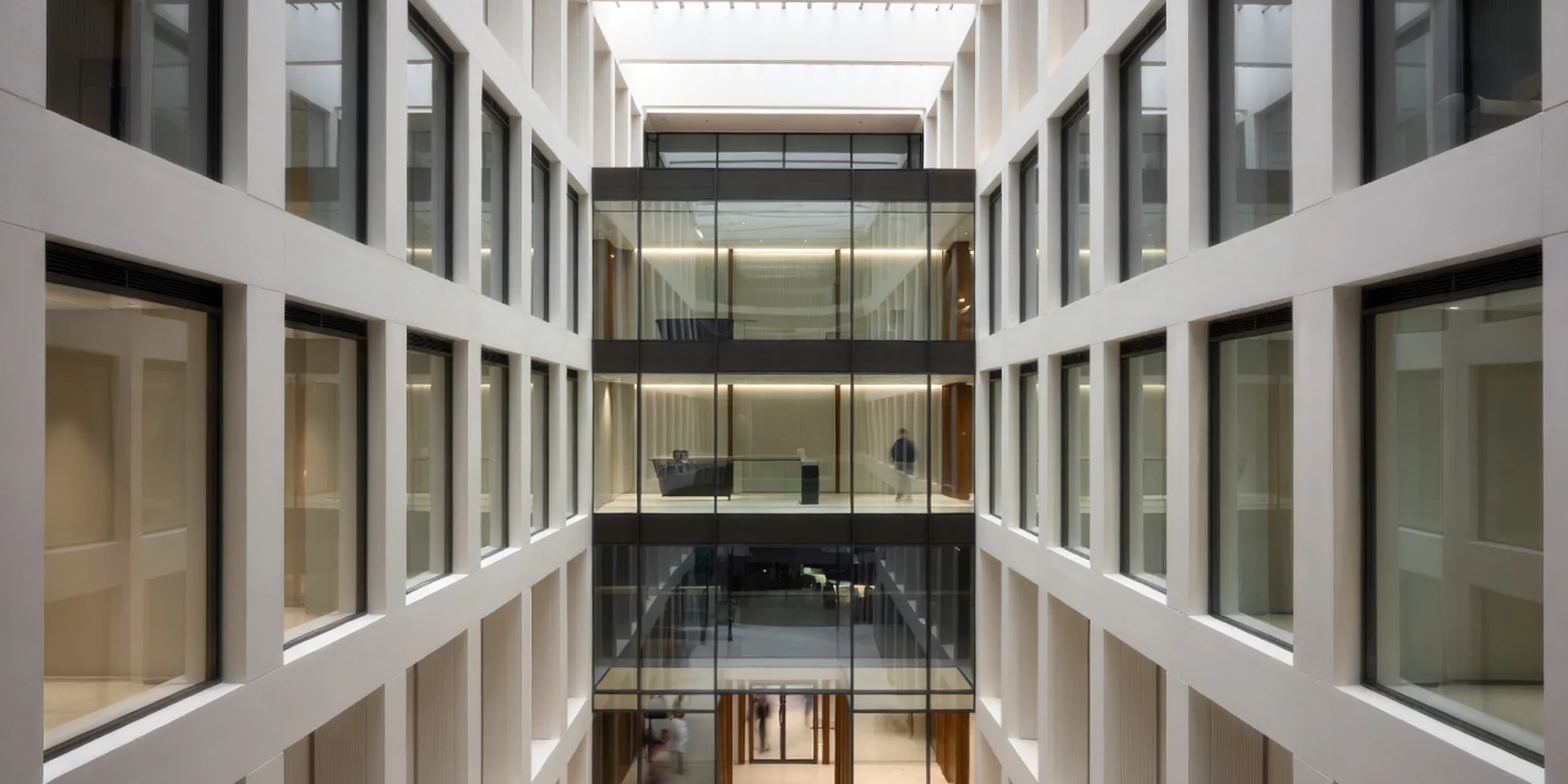 Premium regulatory-hosting atrium with glass-fronted private suites and a mezzanine